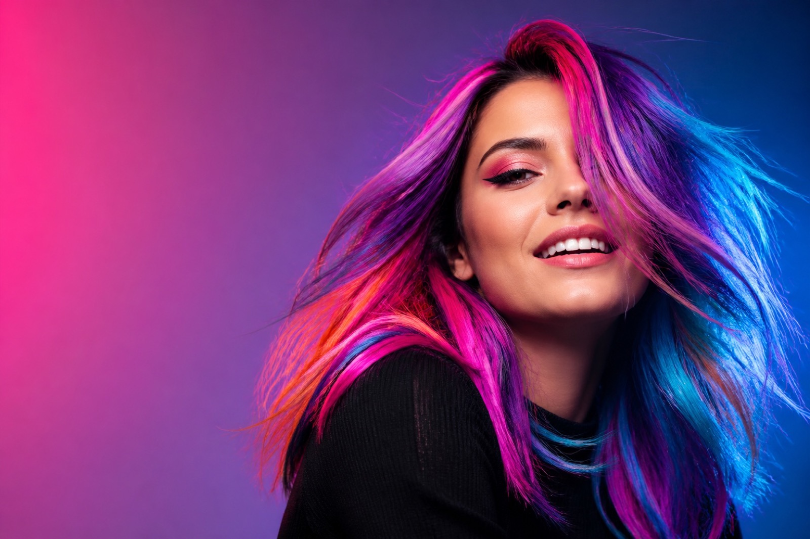 Jeune femme aux cheveux ornés de mèches Crazy Color roses, violettes, bleues et orange
